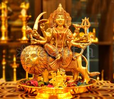 a golden statue of the hindu god sitting on top of a lion