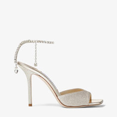 Blurring the lines between shoes and jewellery, the Saeda sandals in platinum ice with a dusty glitter finish are instantly recognisable as Jimmy Choo. Made in Italy, a delicate crystal chain suspends a single crystal and gently adorns the ankle like jewellery, while the meticulously crafted crystals also drip gracefully down the line of the heel. Striking and statement, this pointed pair is set on a slim heel. Jimmy Choo Saeda, Jimmy Choo Bridal, Glitter Sandals, Satin Pumps, Crystal Chain, Jimmy Choo Shoes, Footwear Design Women, Crystal Embellishment, Suede Ankle Boots