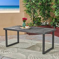 a wooden table sitting on top of a patio next to a planter filled with flowers