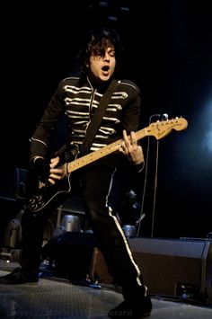 a young man playing an electric guitar on stage