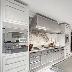 a large kitchen with stainless steel appliances and marble counter tops, along with white cabinets