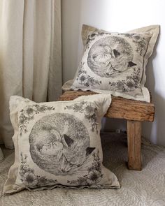 two pillows sitting next to each other on top of a wooden bench in front of a window