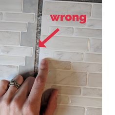 a person is pointing to the wrong direction on a tile wall