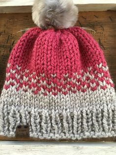 a red and white knitted hat sitting on top of a wooden table