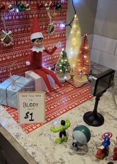 an elf sitting on top of a counter next to christmas decorations