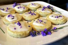 there are many small pastries on the plate with purple flowers and lavender sprinkles