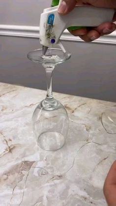 someone is using an electric toothbrush to clean a wine glass on a marble countertop