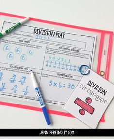 two division mats with markers and pencils next to them