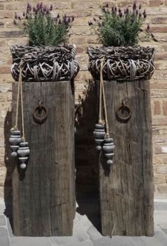 two wooden vases with plants in them on the side of a road next to a brick wall