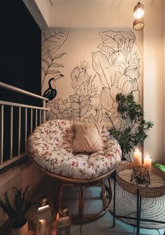 a room with some plants and candles on the floor next to a wall that has a bird drawn on it