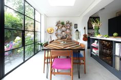 a dining room table and chairs in front of large windows