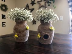 two vases with flowers in them sitting on a table next to a star wall