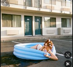 a woman laying on top of an inflatable pool next to a tall building