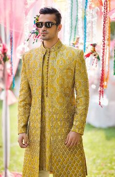 a man in a yellow suit and sunglasses standing next to a tent with decorations on it