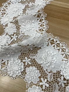 white lace on wood flooring with flowers and leaves in the center, ready to be sewn