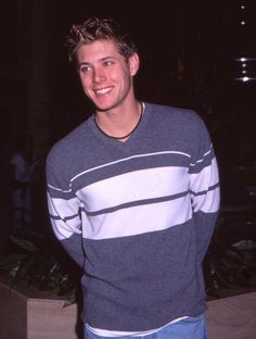 a young man standing in front of a plant