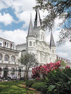 a large white building with two towers on it's sides and pink flowers in the foreground