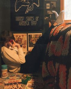 a woman sitting on the floor talking on her cell phone while looking at pictures and posters