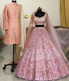 two mannequins with pink and gold gowns on display next to each other