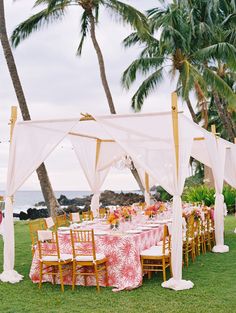 an outdoor wedding setup with pink and white linens, draping over the head table