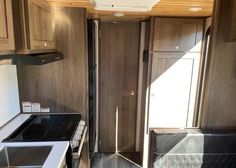 the interior of an rv with wood paneling and white counter tops, black appliances