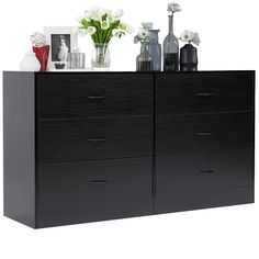 a black dresser with flowers and vases on top