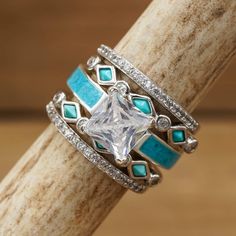 a close up of a ring on top of a wooden stick with turquoise and white stones