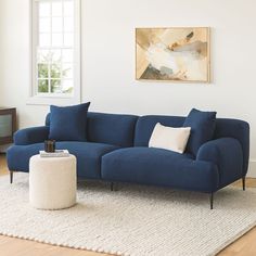 a blue couch sitting on top of a white rug in a living room next to a window