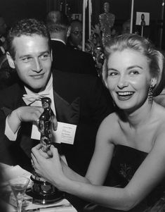 a man and woman sitting at a table with an award