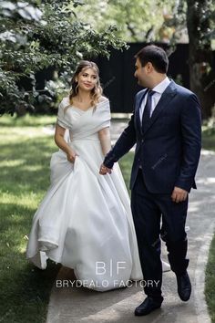 the bride and groom are walking hand in hand through the park together, holding hands