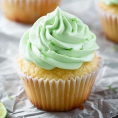 cupcakes with green frosting and lime zest on the top are sitting on aluminum foil