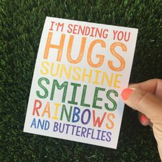 someone holding up a card that says i'm sending you hugs sunshine smiles rainbows and butterflies