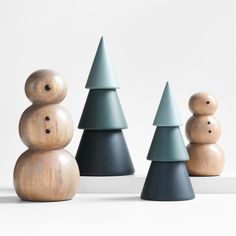 three wooden christmas trees and one snowman made out of wood, with black bases