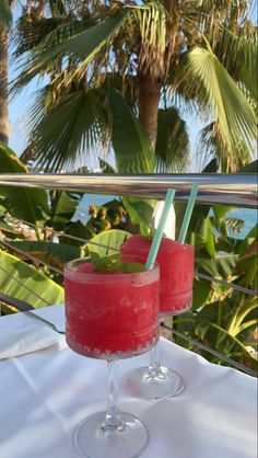 two glasses filled with watermelon drink sitting on top of a white table cloth