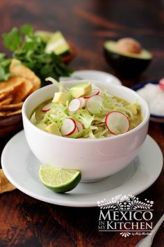 a white bowl filled with soup next to tortilla chips and cilantro