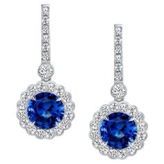 A classic pair of ”Princess Diana style” earrings, featuring 6.37 carats of Ceylon blue sapphires dazzle in divine platinum. The gorgeous sapphires are floating inside sparkling white halos of high-quality, scallop-set, round brilliant cut diamonds weighing 1.81 carats. Earrings are certified by the Gemological Institute of America. Luxury Platinum Blue Earrings, Luxury Blue Platinum Earrings, Elegant Blue Gia Certified Diamond Earrings, Classic Blue Platinum Earrings, Blue Sapphire Diamond Earrings With Brilliant Cut, Blue Halo Earrings For Formal Occasions, Formal Blue Halo Earrings, Blue Tanzanite Brilliant Cut Earrings, Brilliant Cut Tanzanite Blue Earrings