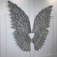 two large metal wings are hanging on the side of a white door with gold glitters