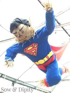 a scarecrow dressed as superman hanging from wires