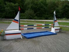 two small sail boats sitting on top of a blue pool in the middle of a dirt field