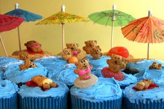 there are cupcakes with teddy bears and umbrellas on the top one is blue