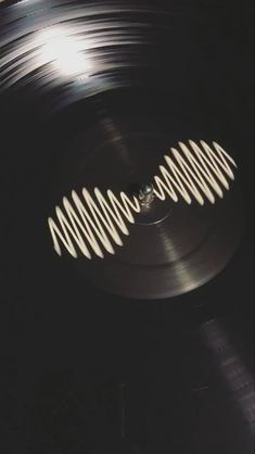 an old record with white spirals on the side and light coming from behind it