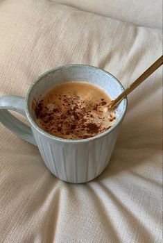 a cup of hot chocolate with cinnamon sprinkles in it on a bed