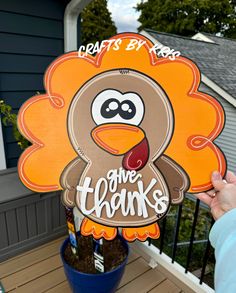 a person holding up a cardboard turkey sign with the words give thanks written on it