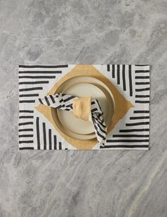 a place setting with black and white striped napkins, gold plates and silverware