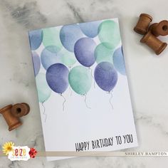 a birthday card with balloons on it next to some wood spools and rubber stamps