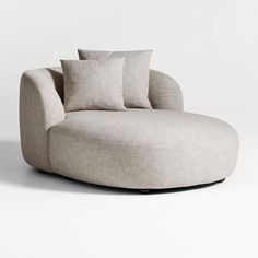 a round couch with three pillows on it's back and one pillow in the middle