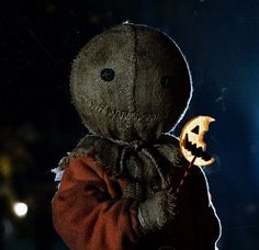 a creepy doll with a pumpkin in its hand