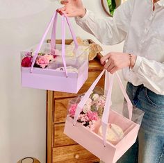 the woman is holding two bags with cupcakes in them and one bag has flowers on it