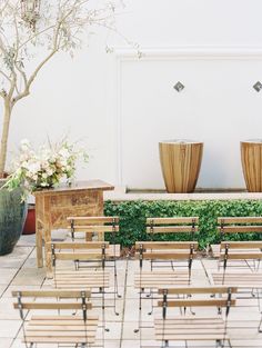 rows of wooden chairs sitting next to each other in front of a wall with vases on it