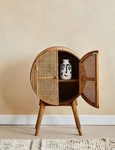 a small wooden cabinet with a vase in the center and a rug on the floor